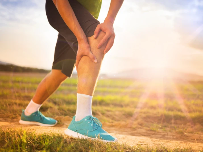 Man Touching Painful Knee While Outside on a Hike